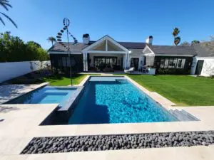 A pool with a fountain and a house in the background.