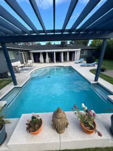 A pool with a blue pergola and two planters