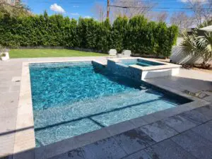 A pool with a stone wall and a bench