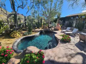 A pool with a large rock wall and plants.