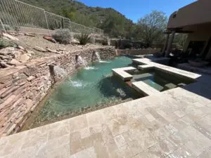 A pool with water jets and rocks in the background.