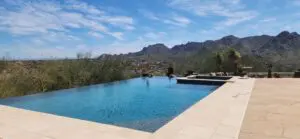 A pool with a mountain view and a person sitting on it.