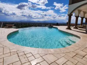 A pool with a view of the sky and mountains.