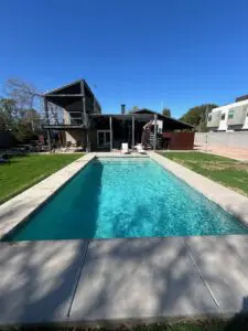 A pool with a large house in the background.