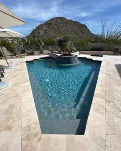 A pool with a large fountain and a mountain in the background.