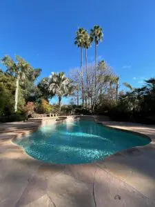 A pool with water jets and palm trees in the background.