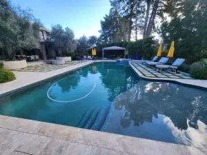 A pool with chairs and umbrellas in the background.