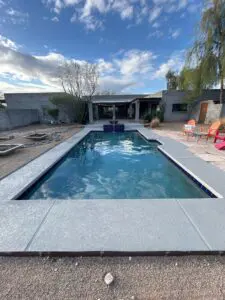 A pool with a large concrete deck and water features.