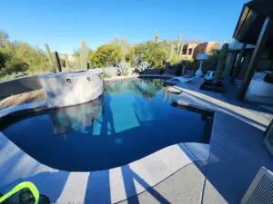 A pool with a large concrete deck and a swimming pool.